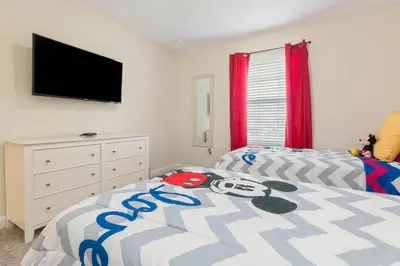 a bedroom with two beds and a flat screen tv at Villa Kerpen - Storey Lake in Kissimmee