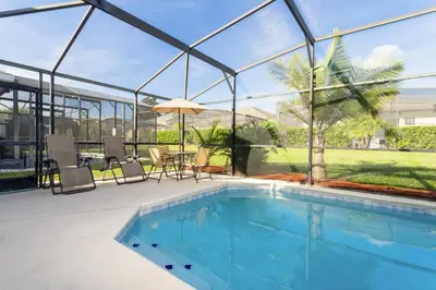 a swimming pool with a glass house with a table and chairs at Villa Helena, Windsor Palms in Kissimmee