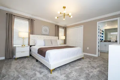 a bedroom with a white bed and a chandelier at Villa Smile, Storey Lake in Kissimmee