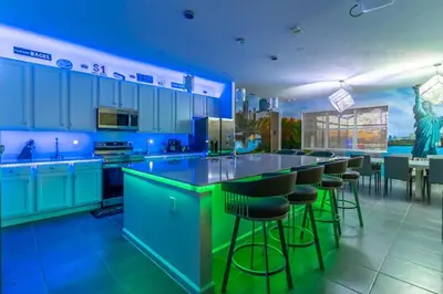 a large kitchen with blue cabinets and bar stools at Brand New 15BR Mansion Pool Spa Close to Disney in Kissimmee