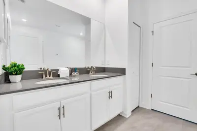 a white bathroom with two sinks and a mirror at Brand New Luxury 9BR Villa Pool Spa Game Room in Kissimmee