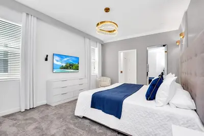 a white bedroom with a blue and white bed at Brand New Luxury 9BR Villa Pool Spa Game Room in Kissimmee