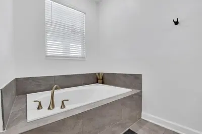 a bath tub in a bathroom with a window at Brand New Luxury 9BR Villa Pool Spa Game Room in Kissimmee