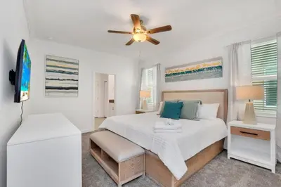 a white bedroom with a bed and a ceiling fan at Brand New Storey Lake 10 Bedroom Villa with Pool in Kissimmee