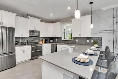 a kitchen with white cabinets and a table with hats on it at Brand New Storey Lake 8BR Villa with Lake View in Kissimmee