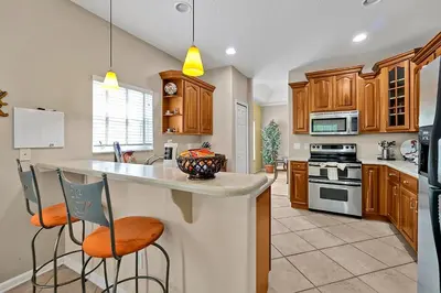 a kitchen with wooden cabinets and a island with bar stools at 11326 CYPRESS TRAIL DRIVE ORLANDO 3BED in Orlando