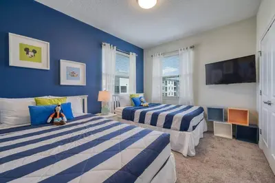 a blue bedroom with two beds and a tv at 3 Bed Condo Close to Disney at Storey Lake in Kissimmee