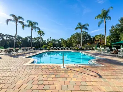 a swimming pool with chairs and palm trees at CCL8569 in Kissimmee