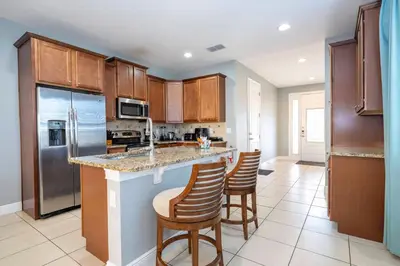 a kitchen with wooden cabinets and a island with bar stools at Classic 8bd house - Encore Reunion Close to Disney in Orlando
