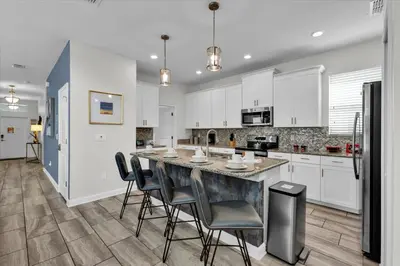 a kitchen with white cabinets and a large island with chairs at SHD4724 in Kissimmee