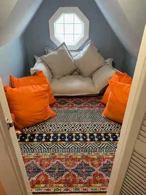 a couch with orange and white pillows on a rug at The Famous Houseboat in Sanford in Sanford