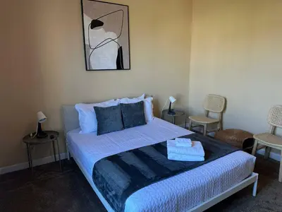 a bedroom with a bed with two chairs and a painting at Cozy condo Just a few minutes from Disney in Kissimmee