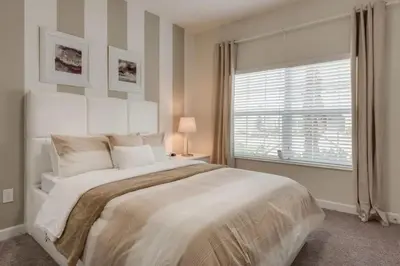 a white bedroom with a large bed and a window at 4QT Elegante Casa c/ Piscina – 10 Min da Disney! in Kissimmee