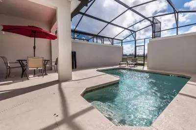 a swimming pool with an umbrella and a table and chairs at 4QT Elegante Casa c/ Piscina – 10 Min da Disney! in Kissimmee