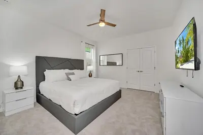 a white bedroom with a bed and a ceiling fan at 2525 Shanti Amazing 15 Suites Mansion in Kissimmee