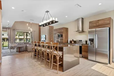a kitchen with a stainless steel refrigerator and wooden cabinets at Minutes to Disney Chic Dream Villa with Stunning Patio and Resort Perks in Orlando