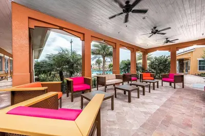 a patio with colorful chairs and tables and windows at Carri-Vision Suite in Kissimmee