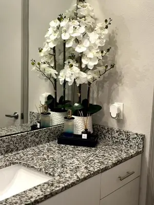 a bathroom counter with a sink and white flowers at Carri-Vision Suite in Kissimmee