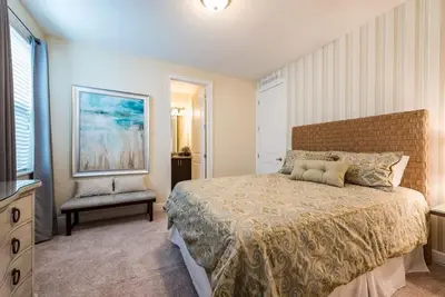a bedroom with a large bed and a chair at Elegant 8BR Encore Resort Pool w Spa GameRoom Single Family in Orlando