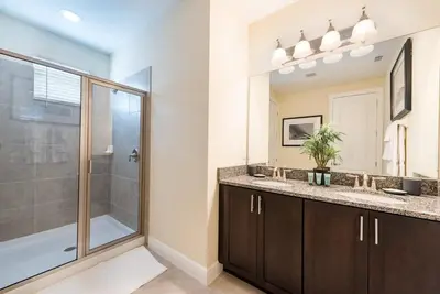 a bathroom with a shower and a sink and a mirror at Elegant 8BR Encore Resort Pool w Spa GameRoom Single Family in Orlando