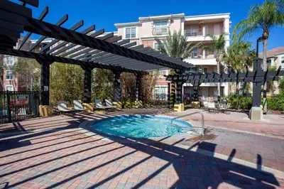 a swimming pool with an umbrella and chairs and a building at Comfortable 3BR Near Convention Center & Epic Park in Orlando