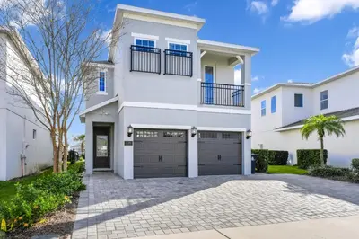 a white house with a garage at Magnificent Home With Private Pool, Theater & Game Room Near Disney With Waterpark & Resort Access At Encore Resort - 230Bu in Kissimmee