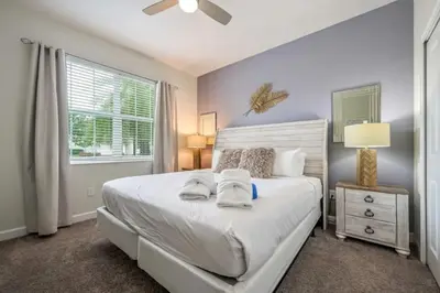 a bedroom with a white bed and a window at Casa 5Q | Piscina Privativa & Vista para o Lago in Kissimmee