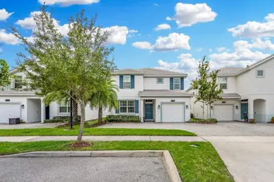 a large white house with a tree in the driveway at Casa 5Q | Piscina Privativa & Vista para o Lago in Kissimmee