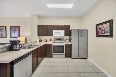 a kitchen with wooden cabinets and stainless steel appliances at Perfect Townhome Near Disney in Orlando