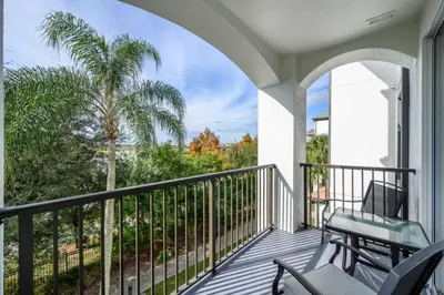 a balcony with chairs and a palm tree at Epic Universe New Deluxe Condo, Vista Cay - 3022 in Orlando