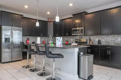 a kitchen with black cabinets and a counter with bar stools at Villa 6Q Storey Lake – 10 min da Disney in Kissimmee