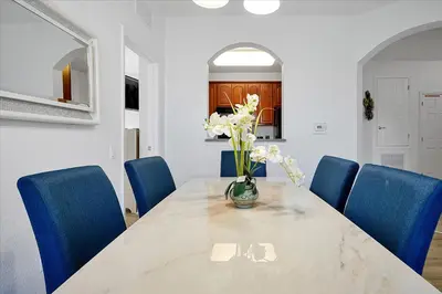 a dining room table with blue chairs and a vase of flowers at Luxury Epic Universe Condo, Vista Cay - 3028 in Orlando