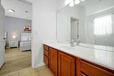 a white bathroom with a sink and a bedroom at Luxury Epic Universe Condo, Vista Cay - 3028 in Orlando