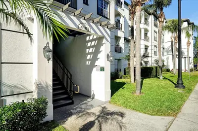 a white apartment building with a gate and palm trees at Luxury Epic Universe Condo, Vista Cay - 3028 in Orlando
