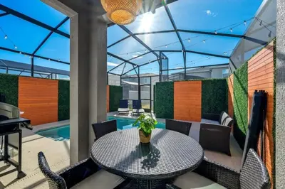 a patio with a table and chairs and a pool at Refúgio 5 Quartos c/ Piscina – Perto da Disney in Kissimmee