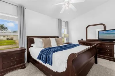 a bedroom with a bed and a flat screen tv at Cozy 5BR Near Disney Mickey Pool in Kissimmee