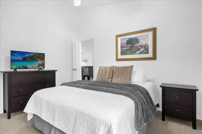 a white bedroom with a bed and a dresser at Cozy 5BR Near Disney Mickey Pool in Kissimmee