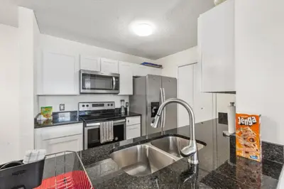a kitchen with white cabinets and a stainless steel sink at NEW London House Orlando Airport Private Condo in Orlando