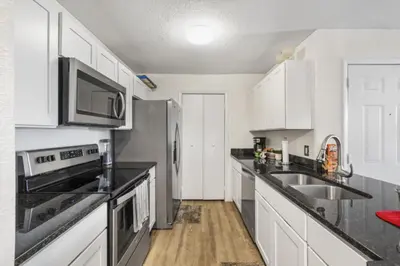 a kitchen with white cabinets and stainless steel appliances at NEW London House Orlando Airport Private Condo in Orlando