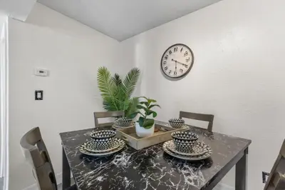 a dining room table with a clock on the wall at NEW London House Orlando Airport Private Condo in Orlando
