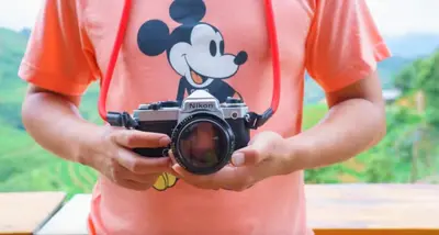 a person holding a camera with a mickey mouse on it at King Bed Theme Park Hotel Free Shuttle Included in Orlando