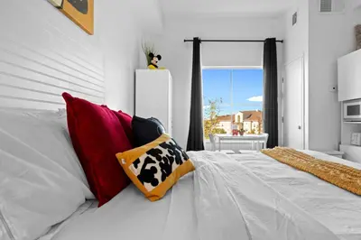 a bedroom with a white bed with red and yellow pillows at King Bed Theme Park Hotel Free Shuttle Included in Orlando