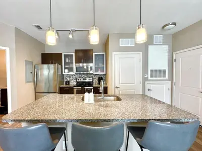 a kitchen with a large counter with blue chairs at Modern Apt in Lake Nona, 10min to ORL Airport in Orlando