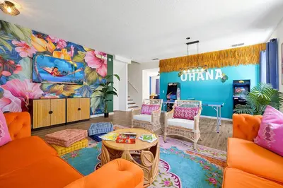 a living room with orange furniture and a colorful mural at Lilo & Stitch Themed Villa 10 Min to Disney! Heated Pool & Game Room in Orlando
