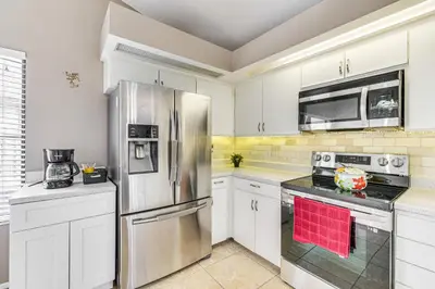 a kitchen with white cabinets and a stainless steel refrigerator at Swim, Golf and Relax Lovely Home in Lake Mary in Lake Mary