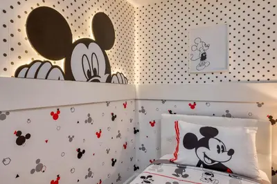 a bedroom with a bed with a mickey mouse wallpaper at Luxuosa Villa 4Q c/ Piscina | 10 min da Disney! in Orlando