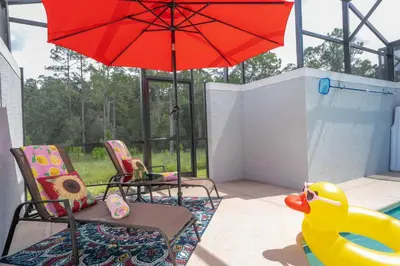 a patio with a red umbrella and chairs and a rubber duck at Stunning 4Bd Close to Disney at Storey Lake Resort 2569 in Kissimmee