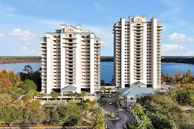 two tall white buildings next to a body of water at Disney Dream Condo & Lake View Awaits! in Orlando