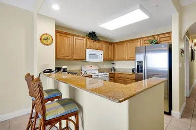 a kitchen with wooden cabinets and a stainless steel refrigerator at Disney Dream Condo & Lake View Awaits! in Orlando