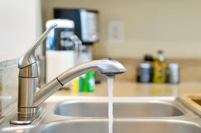 a kitchen sink with water running from a faucet at Living the Disney Dream! Lake View Luxury Condo in Orlando